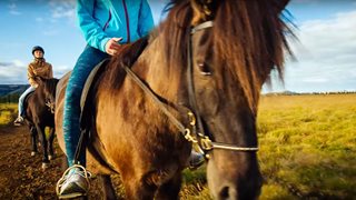 Zwei Urlauberinnen reiten auf lokalen isländischen Pferden