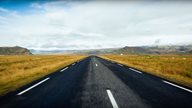 Flache Straße verläuft durch die isländische Landschaft