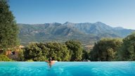 Ein Hotel mit infinity Pool in der Region Calvi mit tollem Blick auf die Berglandschaft Korsikas