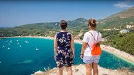 Zwei Frauen genießen die Aussicht auf einen griechischen Hafen und das Meer