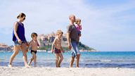 Eine Familie mit 3 kleinen Kindern spaziert am Strand von Calvi