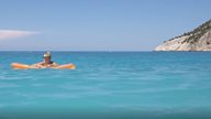 Junge Frau lässt sich auf Luftmatratze in türkis-blauem Meer treiben