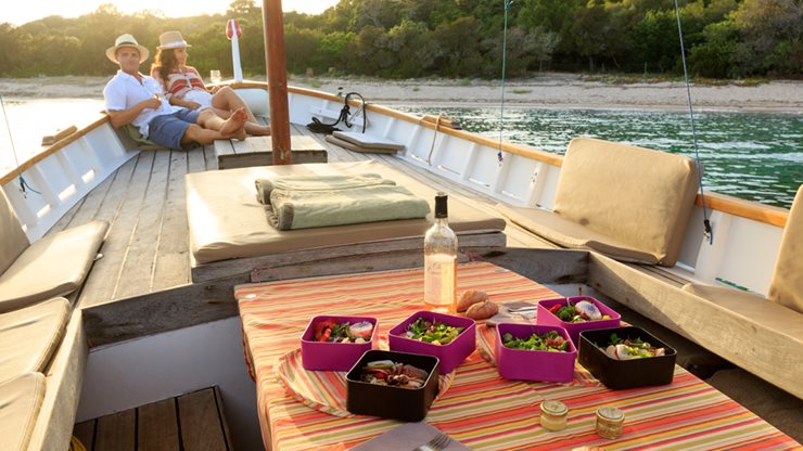 Ein Paar genießt ein Glas Wein in der Abendsonne auf einem Segelboot
